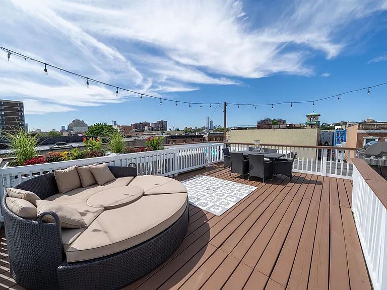 Rooftop lounge with a round daybed, dining table, and string lights